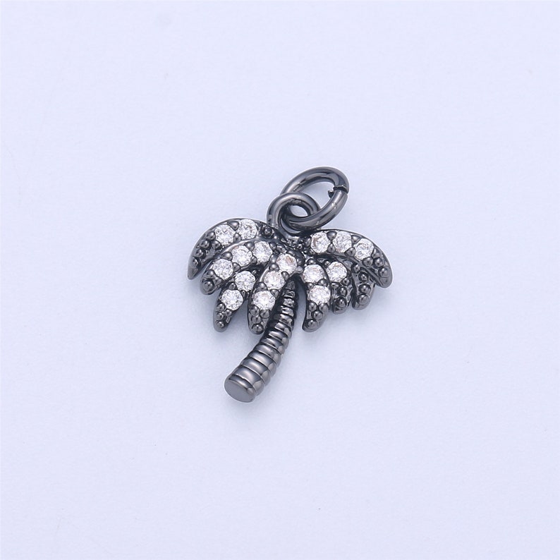 May include: A black palm tree charm with clear crystal accents. The charm has a loop at the top for attaching to a bracelet or necklace.