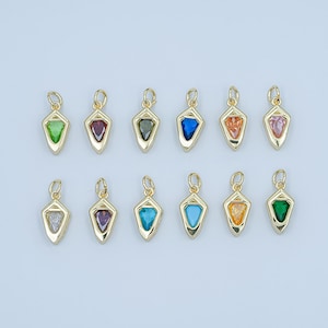 May include: A collection of twelve gold-colored pendants, each featuring a gemstone in various colors, including green, red, blue, and orange. The pendants have a geometric shape and a small loop at the top for attaching to a chain or bracelet.
