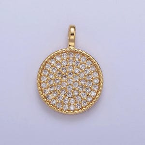 May include: A gold-toned pendant with a round, pave-set design. The pendant is covered in small, clear cubic zirconia stones.