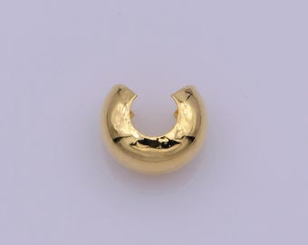 May include: A gold-coloured, C-shaped earring with a smooth, reflective surface. The earring has a rounded, hollow design with a small opening at the top. The jewellery piece is set against a light purple background.