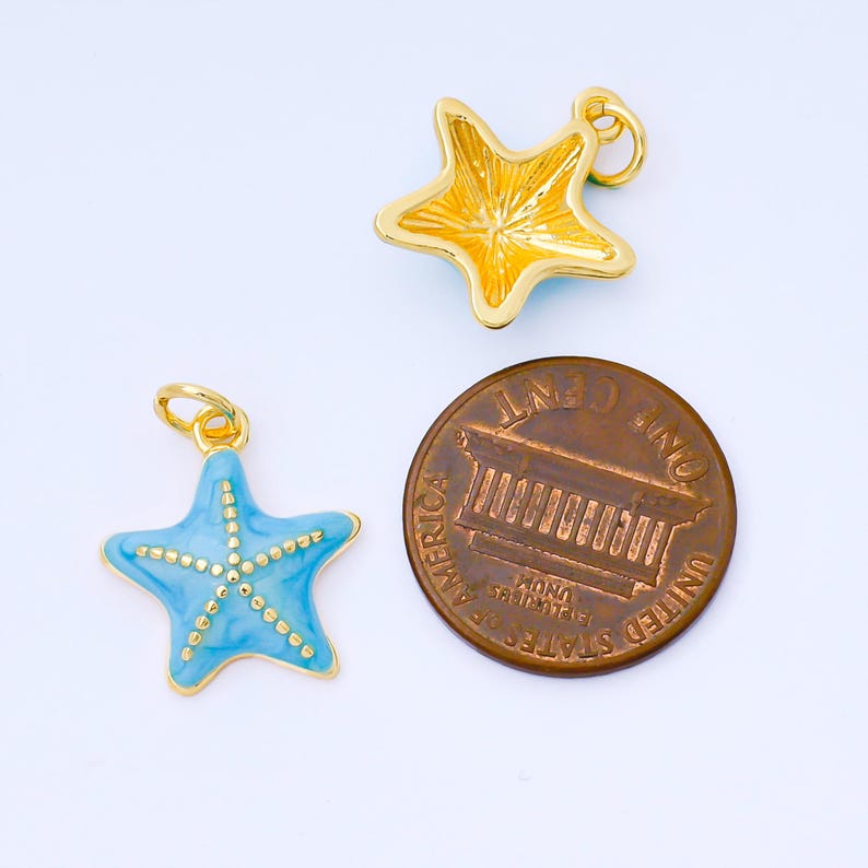 May include: Two starfish charms, one gold and one light blue, with a gold-colored penny for size comparison. The gold starfish has a textured surface. The blue starfish has a gold-colored dotted design. Both charms have a small loop for attaching to a chain or bracelet.