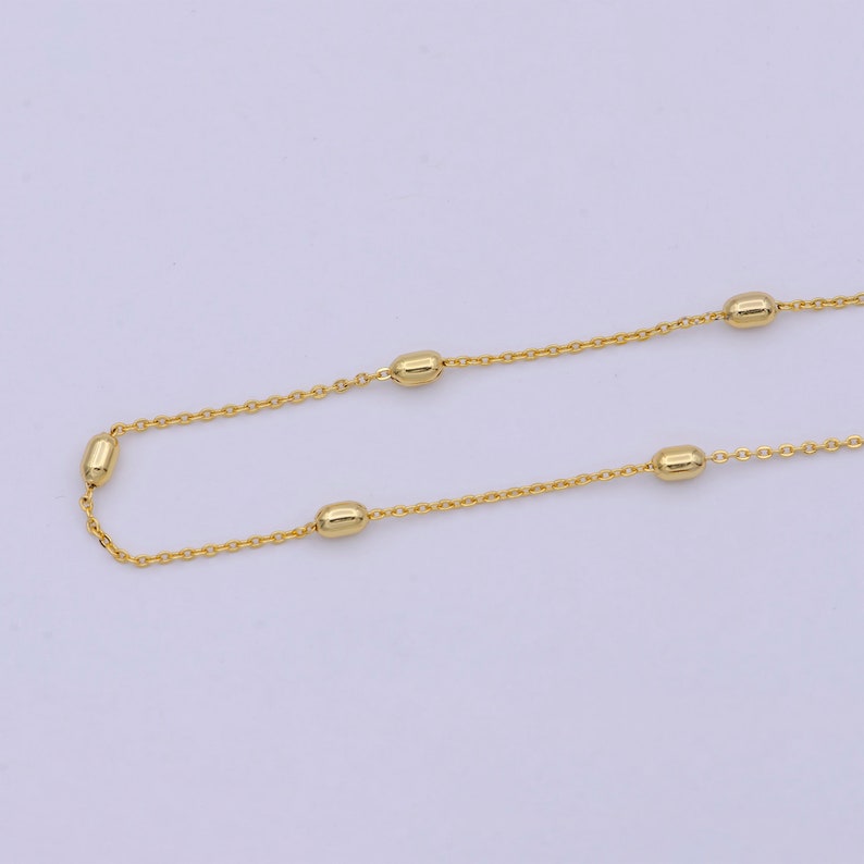 May include: A gold chain necklace with small oval-shaped beads.