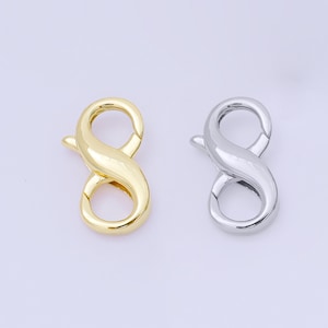 May include: Two lobster claw clasps. One is gold-colored, and the other is silver-colored. Both clasps have a curved, figure-eight shape with a spring-loaded lever for secure closure. These clasps are used for jewelry making and other crafting projects.
