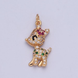 May include: Gold-tone charm featuring a deer with a pink flower on its head and green accents. The deer is covered in clear rhinestones.