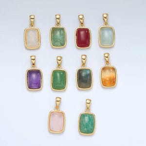 May include: Ten gold pendants with different colored gemstones. The pendants are rectangular and have a gold frame. The gemstones are amethyst, aquamarine, aventurine, citrine, green aventurine, labradorite, moonstone, red jasper, rose quartz, and green amethyst.