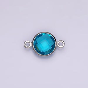 Puede incluir: Un conector plateado con una piedra preciosa redonda de color azul brillante. El conector tiene dos bucles a cada lado para sujetarlo a joyas.
