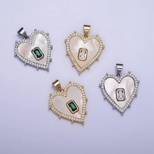 May include: Four heart-shaped pendants with a white mother-of-pearl centre and a green or clear gemstone. Each pendant is surrounded by a border of small clear stones.