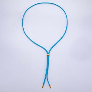 K&ouml;nnte beinhalten: Eine t&uuml;rkisfarbene Halskette mit einem goldfarbenen kreisf&ouml;rmigen Verschluss und goldfarbenen Spitzen. Die Halskette ist ein schlichtes, elegantes Design, perfekt f&uuml;r den t&auml;glichen Gebrauch. Die Halskette besteht aus einem d&uuml;nnen, flexiblen Material.