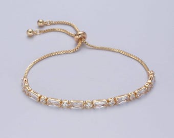 Puede incluir: Un brazalete ajustable de oro con una fila de piedras rectangulares transparentes.