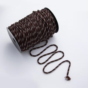 May include: A spool of brown and white patterned rope. The rope is tightly wound on a black plastic spool. A length of the rope extends from the spool, displaying its alternating brown and white design. The rope is suitable for various crafting and decorative projects.