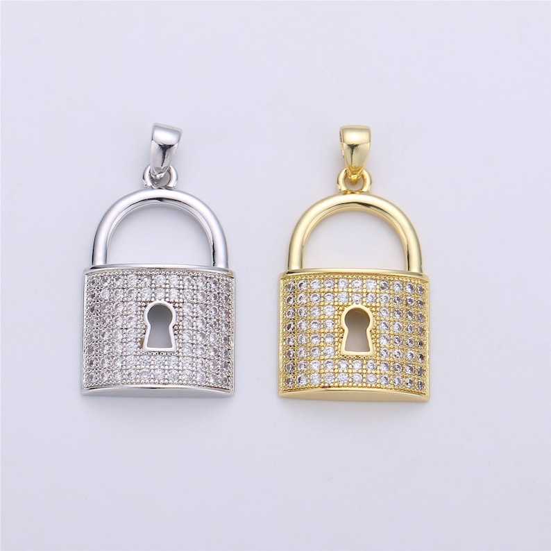 Pu&ograve; includere: Due ciondoli a forma di lucchetto, uno in argento e uno in oro, entrambi con pietre di zircone cubico trasparenti.