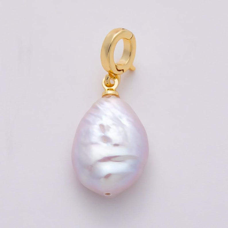 May include: A single gold-colored earring with a large, pear-shaped, iridescent pearl pendant. The pearl has a soft, pinkish-white hue with subtle surface textures. The earring's clasp is a simple, circular design.