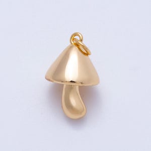 May include: A gold-colored mushroom charm with a rounded cap and stem. The charm has a small loop at the top for attaching to a necklace or bracelet. The mushroom is a shiny, smooth, and three-dimensional design.