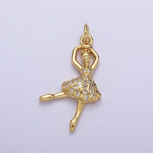 Peut inclure: Breloque ballerine dorée avec des accents de cristal transparent. Le charme est dans une pose de danse avec les bras levés et une jupe.