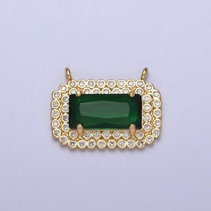 May include: A rectangular emerald-cut green gemstone pendant with a gold-colored frame. The frame is encrusted with small, clear crystals. Two small loops are at the top for attaching to a chain. The pendant is set against a white background.