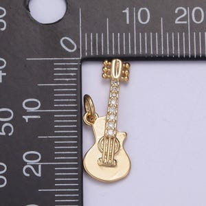 May include: Gold-tone guitar charm with clear rhinestone accents. The charm is approximately 1 inch in length.