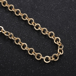 May include: A gold chain necklace with a delicate, round link design. The chain is on a black background.