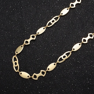 May include: A gold chain necklace with a unique oval link design. The chain is made of metal and has a polished finish.