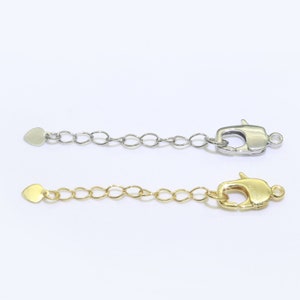 May include: Two extender chains for necklaces or bracelets. The top chain is silver with a heart-shaped end and a lobster clasp. The bottom chain is gold with a heart-shaped end and a lobster clasp.