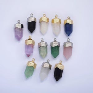 Może przedstawiać: Zestaw 12 zawieszek z kryształowymi końcówkami z złotymi i srebrnymi akcentami. Zawieszki są w różnych kolorach, w tym ametyst, różowy kwarc, czysty kwarc, zielony awenturyn i czarny onyks.