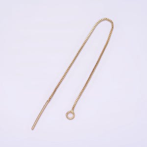 May include: A gold chain earring extender with a small circle at the end. The extender is about 2 inches long.
