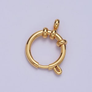 May include: Gold-toned metal clasp with a round ring and a hook closure. The clasp is designed to be used for attaching jewelry or other items.