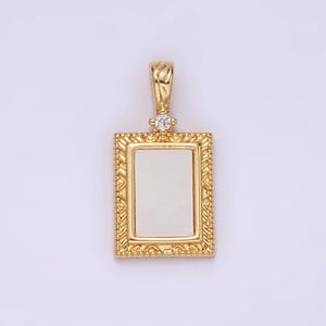 May include: A gold pendant with a rectangular frame and a small clear stone at the top. The frame has a decorative design.