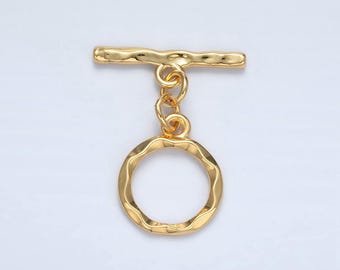 May include: Gold-toned metal toggle clasp with a round, textured ring. The clasp is designed for attaching to jewelry or other accessories.