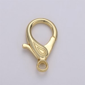 May include: Gold-toned metal lobster clasp with a decorative paisley design. The clasp is about 1 inch in length.