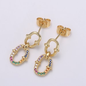 May include: A pair of gold-colored earrings. Each earring features a small, oval-shaped charm with a rainbow of colorful gemstones. The earrings have a post-back closure and a connecting link.