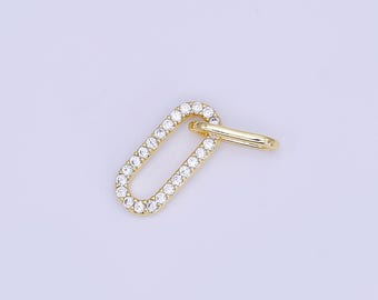 May include: A gold-colored oval charm with a row of clear crystals around the perimeter. A smaller, gold-colored ring is attached to the top of the oval. The charm is set against a light purple background.