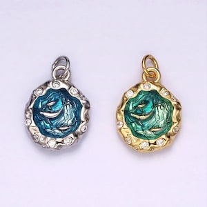 May include: Two silver and gold pendants with a blue and green enamel design of two fish swimming in a circle. The pendants are surrounded by clear rhinestones.