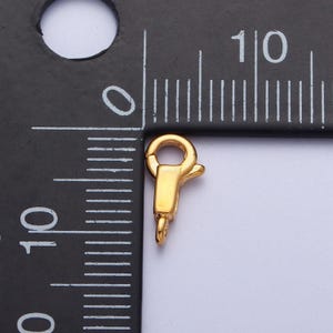 May include: Gold-toned metal clasp for jewellery making, measuring approximately 1 cm in length.