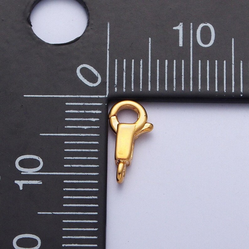 May include: Gold-toned metal clasp for jewellery making, measuring approximately 1 cm in length.
