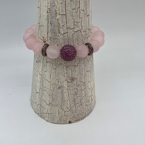 May include: A pink rose quartz beaded bracelet with a pink and silver sparkly accent bead.