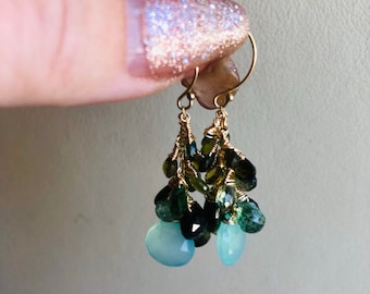 Puede incluir: Pendientes de oro con un racimo de piedras preciosas verdes y azules. Los pendientes son colgantes y tienen un diseño de alambre envuelto.