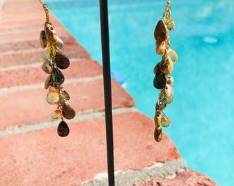 May include: Gold dangle earrings with multiple teardrop-shaped stones in shades of brown, beige, and green.