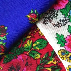 May include: Three fabric swatches with floral patterns. The first swatch is a solid blue with red and yellow flowers. The second swatch is red with green leaves and pink flowers. The third swatch is white with green leaves and pink, yellow, and blue flowers.