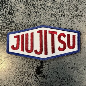 May include: A white patch with a blue border and red embroidered text that reads "JIUJITSU".