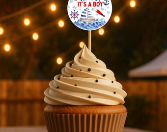 Puede incluir: Un cupcake con glaseado color crema y chispas de chocolate, coronado con un adorno para pastel de temática náutica. El adorno dice "AHOY! IT'S A BOY!" y presenta un velero, un ancla y otros elementos náuticos. El cupcake está en un molde de papel marrón.