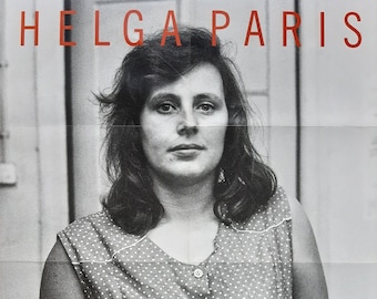 May include: Black and white photograph of Helga Paris, a woman with dark hair and a polka dot shirt. The text "HELGA PARIS" is in red letters at the top of the image. The text "15. September 2004 - 13. Februar 2005 Sprengel Museum Hannover" is at the bottom of the image.