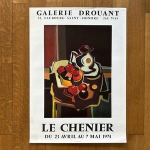 May include: A vintage art poster for Galerie Drouant, featuring a still life painting with red apples and a white and black vase. The poster includes the text "LE CHENIER" and dates from April 23 to May 7, 1974.