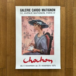 Könnte beinhalten: Ein Vintage-Plakat, das eine Kunstausstellung mit dem Titel "Chahon" in der Galerie Cardo Matignon in Paris bewirbt. Das Plakat zeigt ein Gemälde einer Frau in einem blauen Kleid und einem schwarzen Hut, die auf einem Stuhl sitzt und eine Tasse hält. Der Text auf dem Plakat lautet "Galerie Cardo Matignon, 32, Avenue Matignon, Paris-8", "Chahon" und "du 4 novembre au 25 novembre 1975".