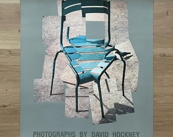 May include: A poster featuring a photograph of a blue metal chair with a bird perched on the back. The chair is partially obscured by overlapping images of itself, creating a fragmented effect. The text "PHOTOGRAPHS BY DAVID HOCKNEY" is printed at the bottom of the poster.