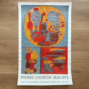Może przedstawiać: Winietkowy plakat reklamujący wystawę sztuki Pierre'a Courtina w maju 1974 w Galerii Georgesa Berniera w Paryżu. Plakat przedstawia abstrakcyjny geometryczny wzór w kolorze czerwonym, żółtym, niebieskim i brązowym.