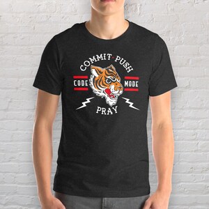 K&ouml;nnte beinhalten: Ein dunkelgraues T-Shirt mit einem Tiger-Motiv und dem Text "Commit Push Code Pray Mode".