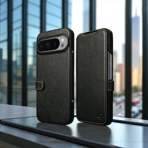 May include: Two black leather phone cases with a textured finish. One case is open, revealing the phone's camera array. Both cases have contrasting tan stitching and a magnetic closure. The cases are displayed against a blurred cityscape background.