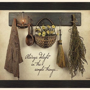May include: A framed rustic wall hanging featuring a wooden rack with a candle, a wooden spoon, a basket of yellow flowers, a small broom, and dried herbs. A checkered cloth hangs on the left. The text reads, "Always delight in the simple things..."