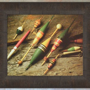 May include: A collection of vintage wooden fishing bobbers with red, green, yellow, and white paint. The bobbers are arranged on a weathered wooden surface.