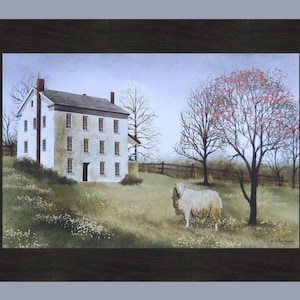 May include: A white farmhouse with a brown roof and many windows sits on a grassy hill. A single sheep stands in the field in front of the house. A tree with red leaves is in the background.